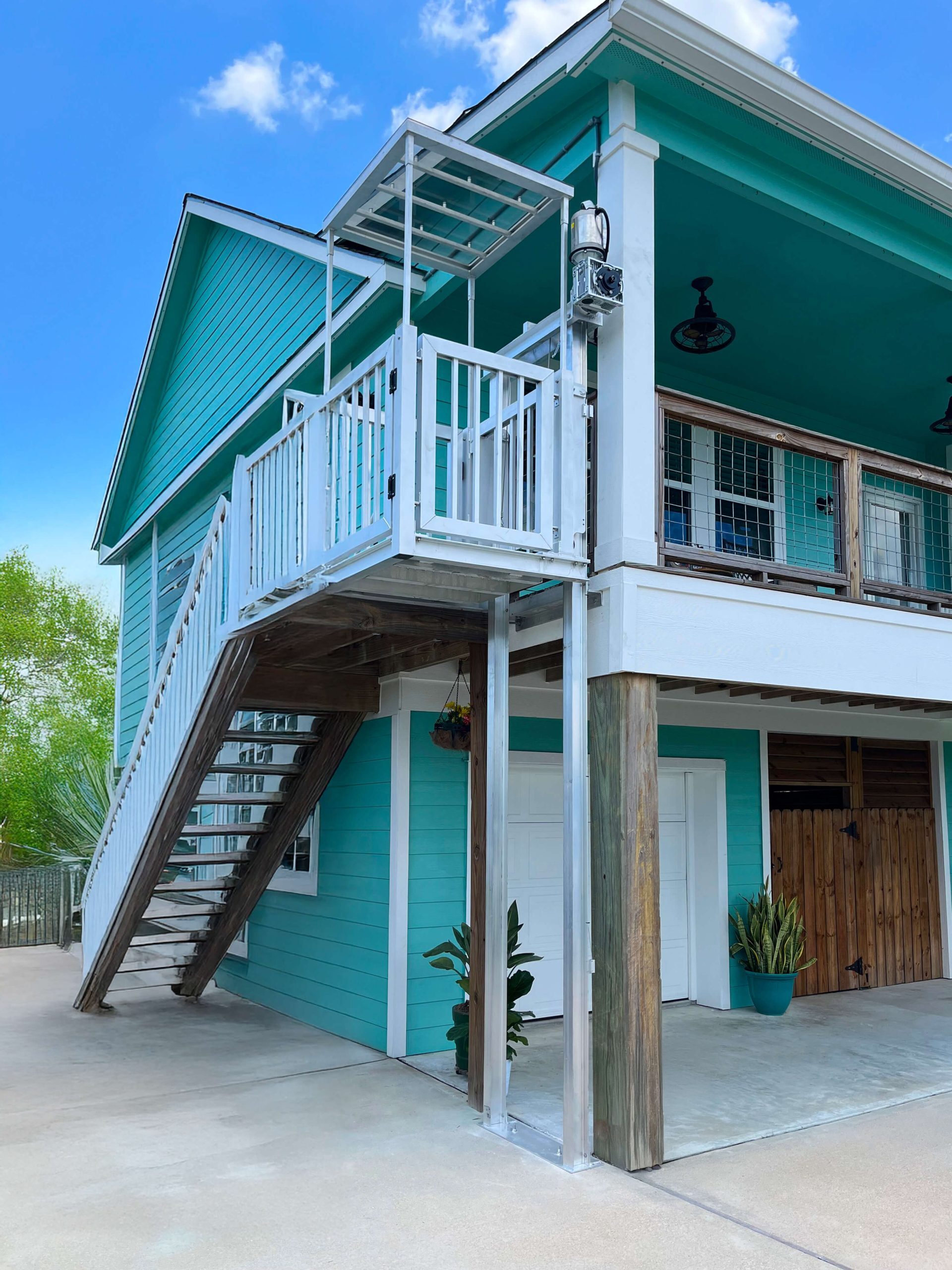 Galaxy Shuttle cargo lift installed on a bright teal coastal beach house