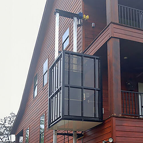 Galaxy Traveler passenger lift on a dark reddish-brown wood-sided home